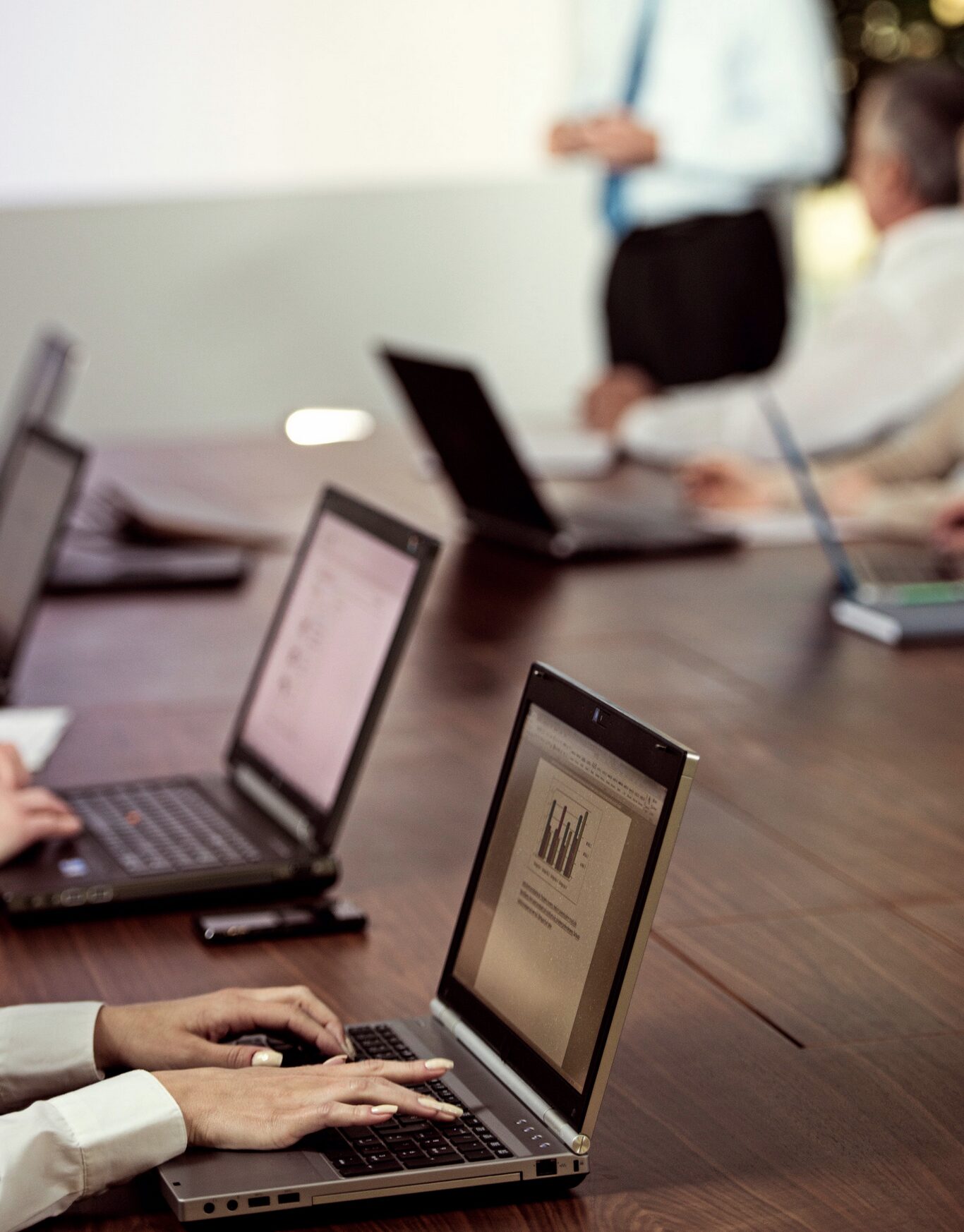 Office workers meeting around a desk, working on laptops.